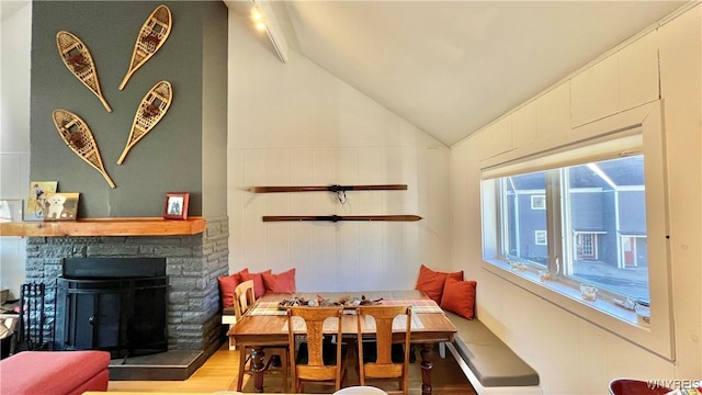 dining area with lofted ceiling, breakfast area, light wood-type flooring, and a fireplace