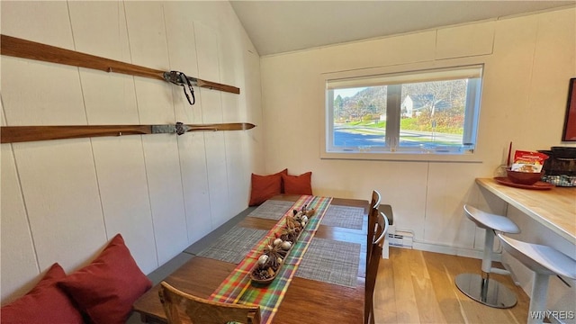 dining area with lofted ceiling, light wood-type flooring, and a baseboard radiator