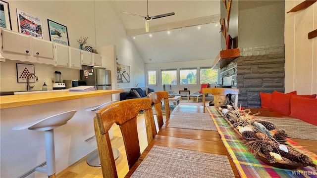 kitchen featuring light wood-style floors, freestanding refrigerator, white cabinets, and high vaulted ceiling