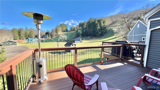 wooden deck featuring a shed, a lawn, and an outdoor structure