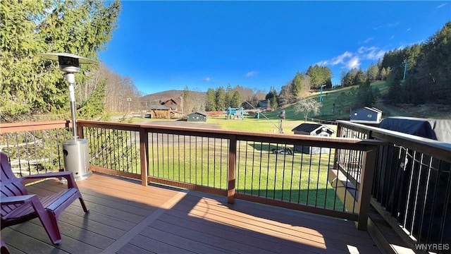 wooden deck featuring a playground and a lawn