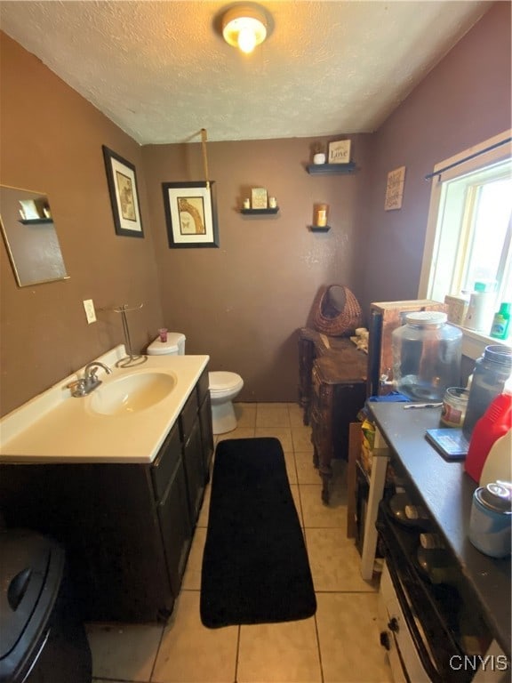 bathroom with toilet, vanity, a textured ceiling, and tile patterned floors