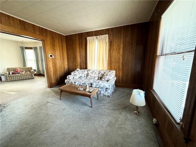 sitting room with wood walls, carpet floors, and ornamental molding