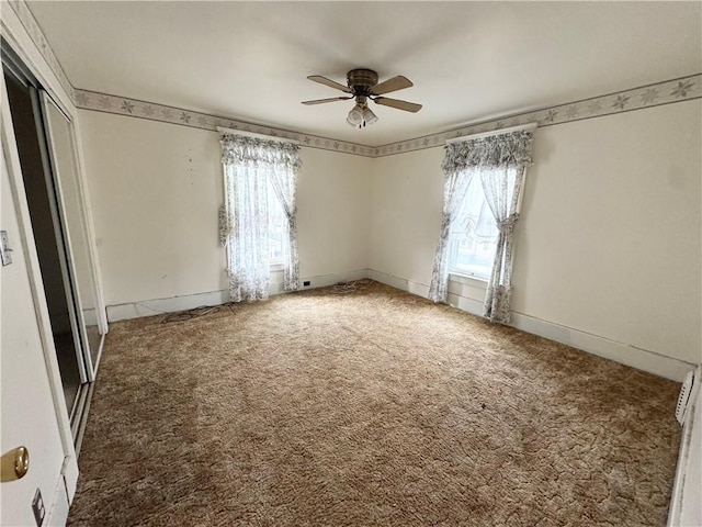 carpeted spare room featuring plenty of natural light and ceiling fan