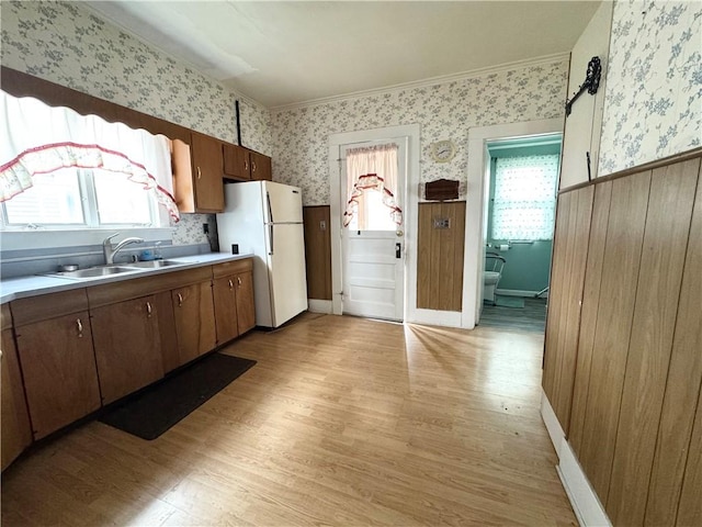 kitchen featuring white refrigerator, light wood-type flooring, sink, and ornamental molding