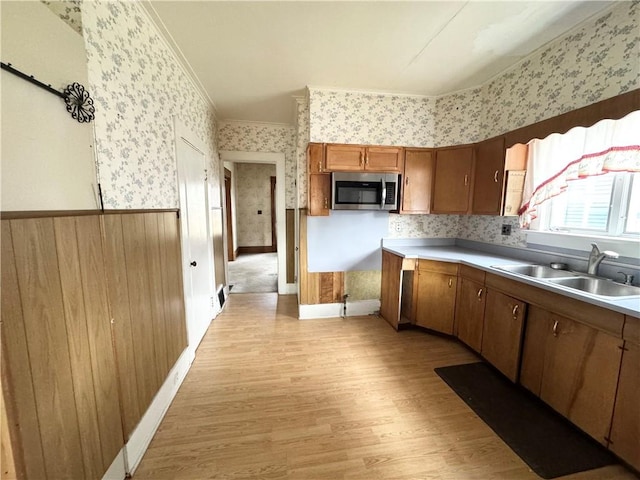 kitchen with crown molding, sink, and light hardwood / wood-style flooring