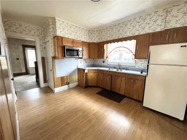 kitchen with white refrigerator, light hardwood / wood-style flooring, ornamental molding, and sink