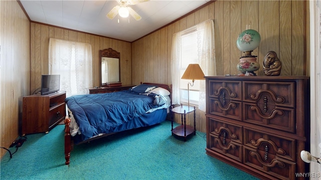 carpeted bedroom featuring wood walls, ceiling fan, and crown molding