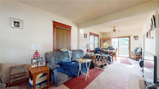 living room featuring a textured ceiling, ceiling fan, and carpet floors