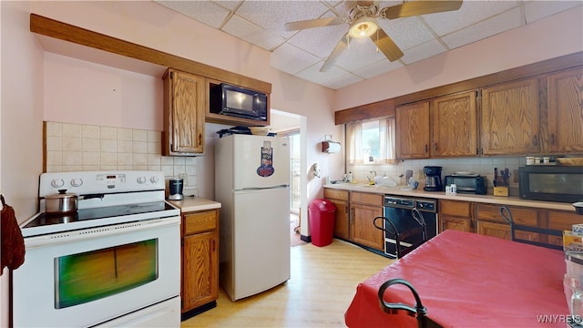 kitchen featuring a paneled ceiling, black appliances, ceiling fan, backsplash, and light hardwood / wood-style flooring