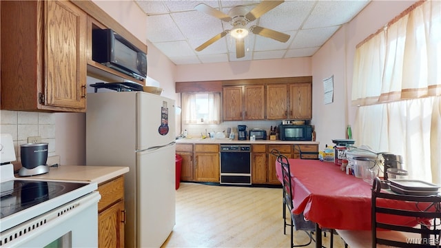 kitchen with decorative backsplash, a paneled ceiling, black appliances, ceiling fan, and light hardwood / wood-style flooring