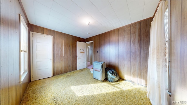 unfurnished bedroom featuring carpet floors, wood walls, and heating unit