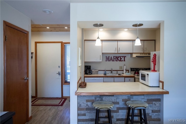 kitchen featuring white appliances, a kitchen breakfast bar, decorative light fixtures, dark hardwood / wood-style flooring, and white cabinetry