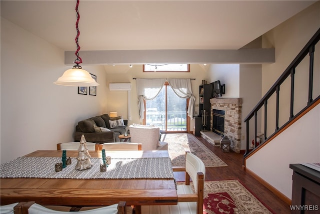 living room featuring hardwood / wood-style flooring, a stone fireplace, and a wall mounted AC