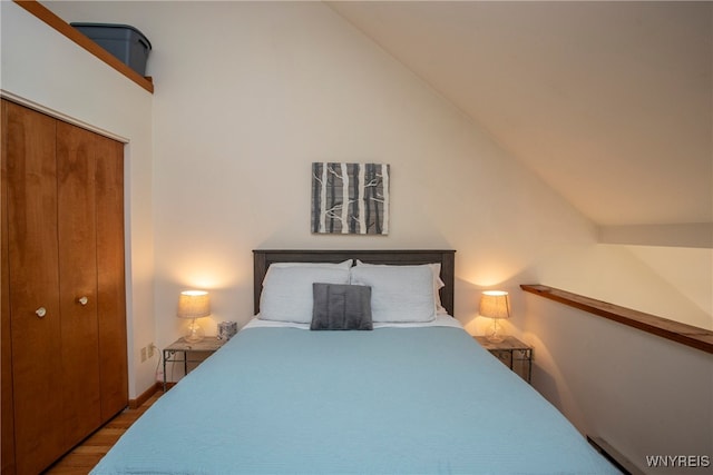 bedroom featuring hardwood / wood-style floors, vaulted ceiling, and a closet