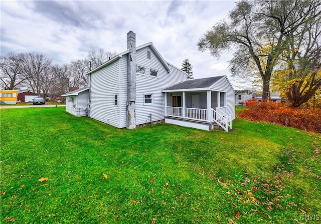 back of house featuring covered porch and a yard