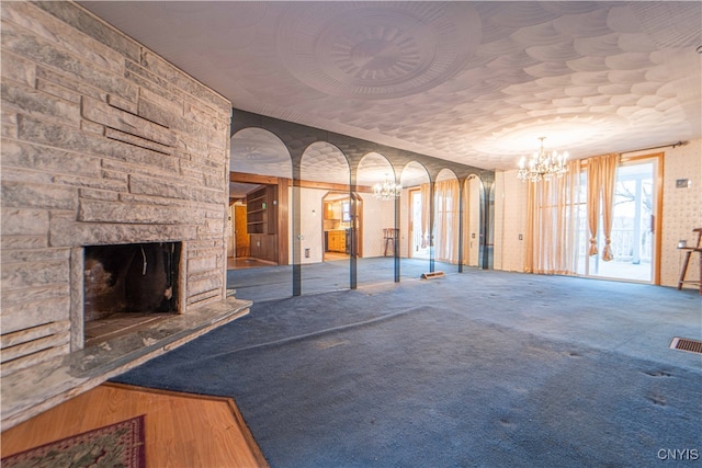 unfurnished living room with a stone fireplace and carpet