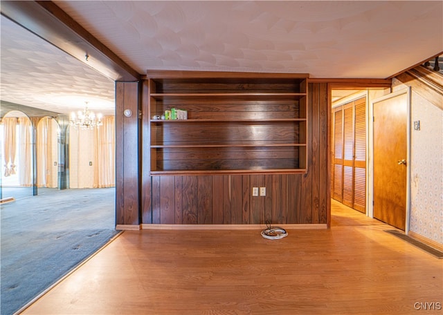 interior space featuring hardwood / wood-style floors, wooden walls, and a notable chandelier