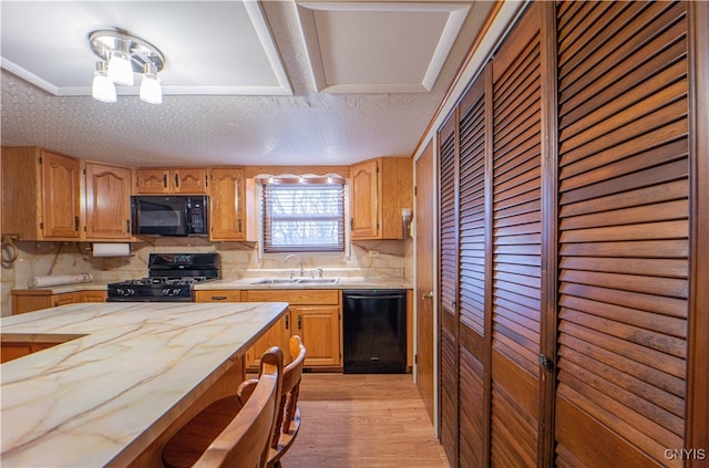 kitchen with black appliances, light wood-type flooring, backsplash, a textured ceiling, and sink