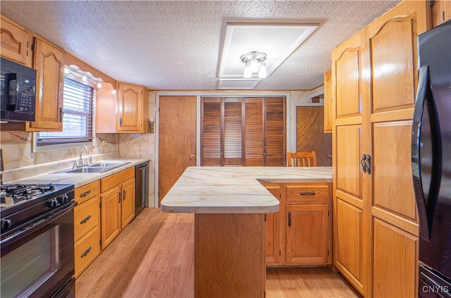 kitchen with black appliances, light hardwood / wood-style flooring, a textured ceiling, and a center island