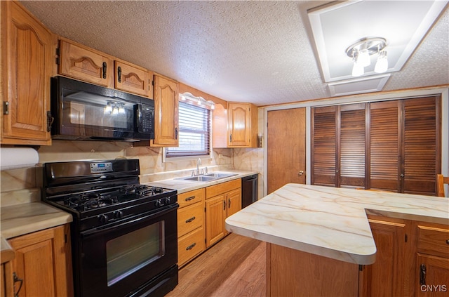 kitchen with black appliances, sink, a textured ceiling, and light hardwood / wood-style floors