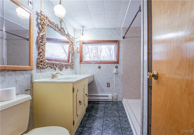 bathroom featuring baseboard heating, tiled shower, vanity, and toilet