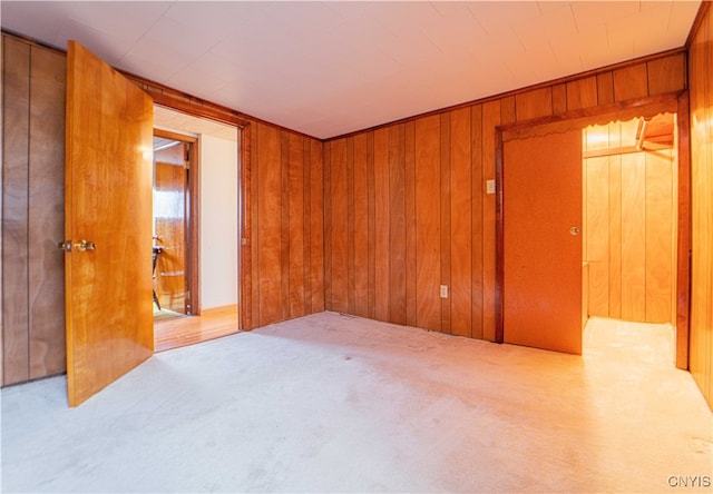 unfurnished bedroom featuring light colored carpet and wooden walls