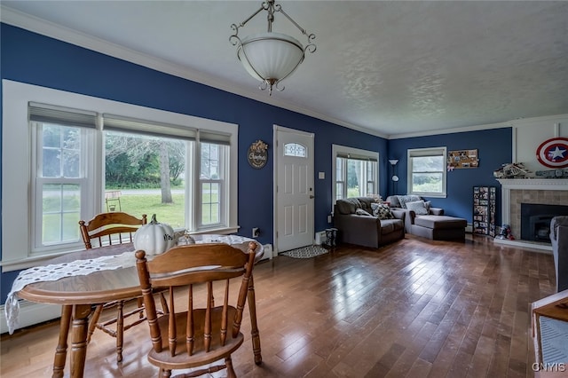 dining room with ornamental molding, a fireplace, dark hardwood / wood-style floors, and plenty of natural light