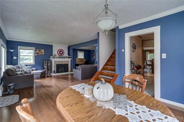 dining area with a tiled fireplace, hardwood / wood-style flooring, and crown molding