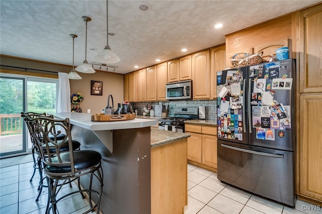 kitchen featuring stainless steel appliances, tasteful backsplash, light tile patterned floors, decorative light fixtures, and a kitchen island