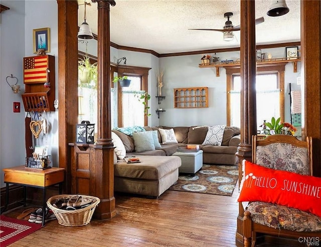 living room with a textured ceiling, hardwood / wood-style flooring, ceiling fan, and ornamental molding