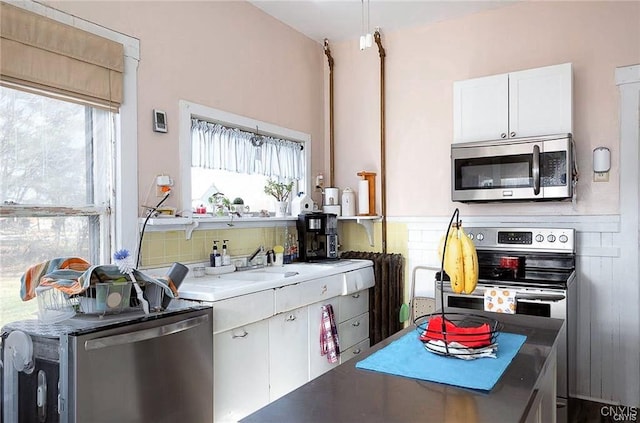 kitchen featuring appliances with stainless steel finishes, backsplash, white cabinetry, and a wealth of natural light