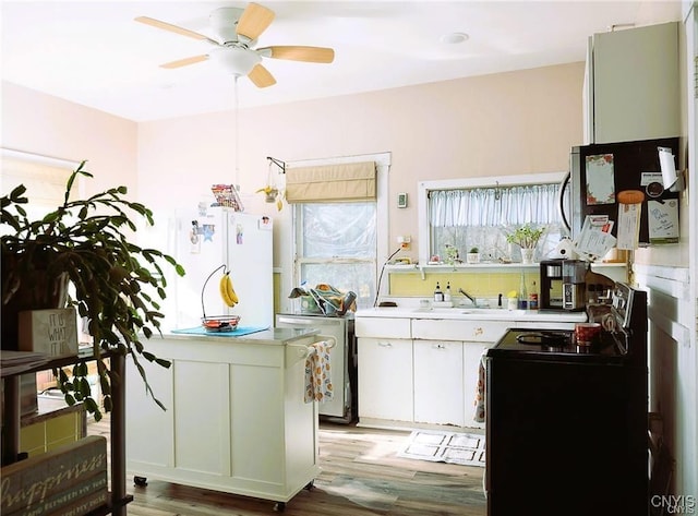 kitchen with ceiling fan, sink, light hardwood / wood-style flooring, white cabinets, and black range with electric stovetop