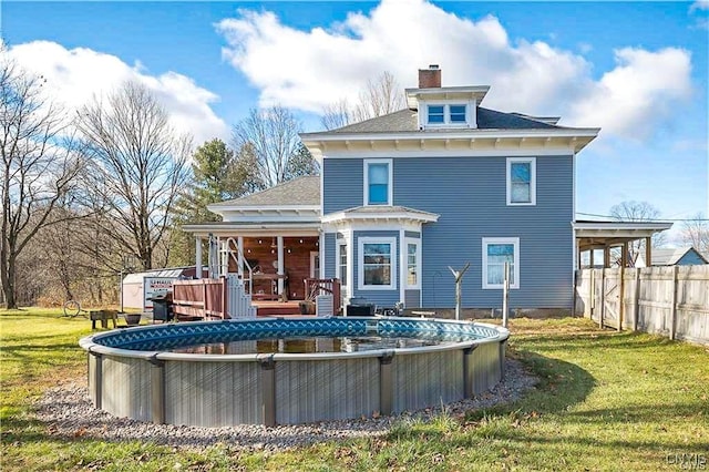 rear view of house featuring a pool side deck and a lawn