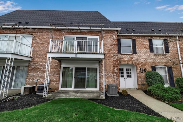 back of house featuring central air condition unit, a balcony, a yard, and a patio