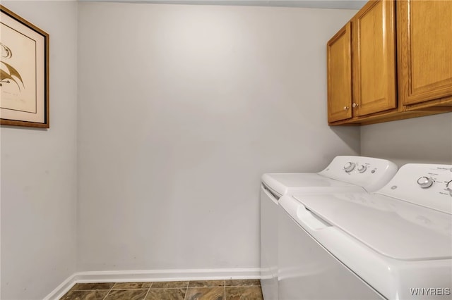 laundry area with dark tile patterned floors, cabinets, and independent washer and dryer