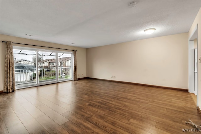 empty room featuring a water view, wood-type flooring, and a textured ceiling