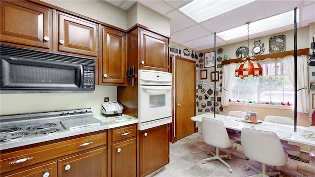 kitchen featuring a drop ceiling, decorative light fixtures, and white appliances