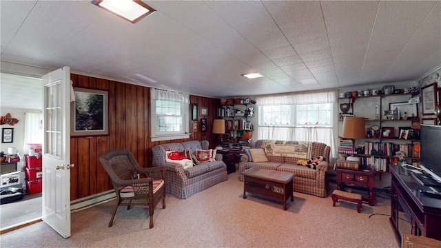 carpeted living room with a baseboard heating unit and wood walls