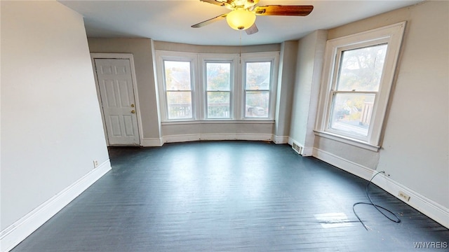 empty room with ceiling fan, plenty of natural light, and dark wood-type flooring