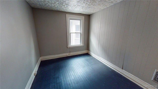 unfurnished room featuring wood walls, a paneled ceiling, and dark hardwood / wood-style flooring