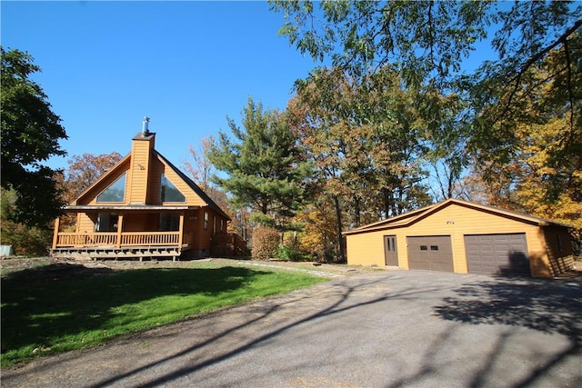 view of home's exterior with an outbuilding, a garage, a lawn, and covered porch