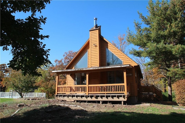 exterior space featuring covered porch, fence, and a chimney