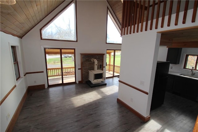 living room featuring wood ceiling, dark wood-style floors, a wood stove, and baseboards