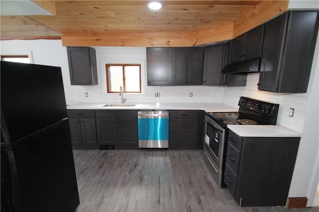 kitchen featuring electric range oven, freestanding refrigerator, stainless steel dishwasher, under cabinet range hood, and a sink