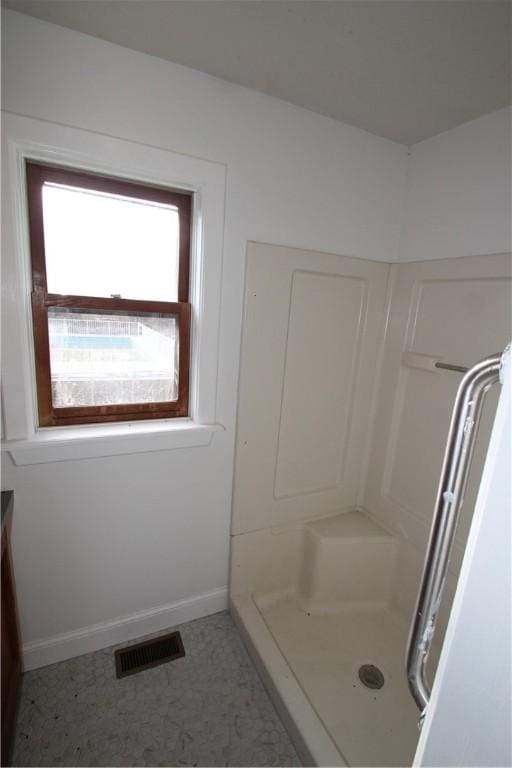 bathroom with a stall shower, visible vents, and baseboards