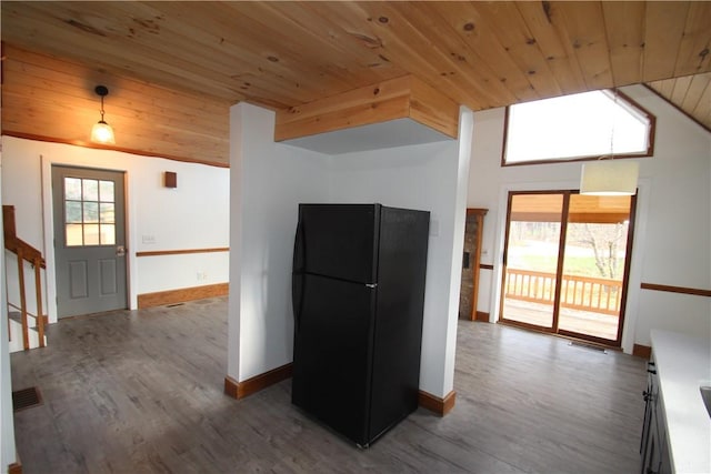 kitchen with lofted ceiling, wood finished floors, light countertops, freestanding refrigerator, and decorative light fixtures