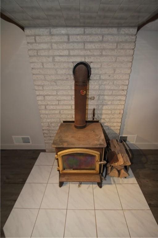 interior details featuring a wood stove, visible vents, baseboards, and wood finished floors