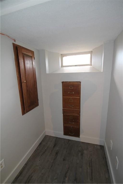 below grade area with dark wood-style flooring and baseboards