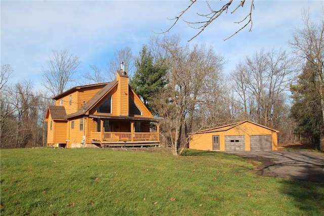 view of home's exterior featuring a lawn, a detached garage, a chimney, covered porch, and an outdoor structure